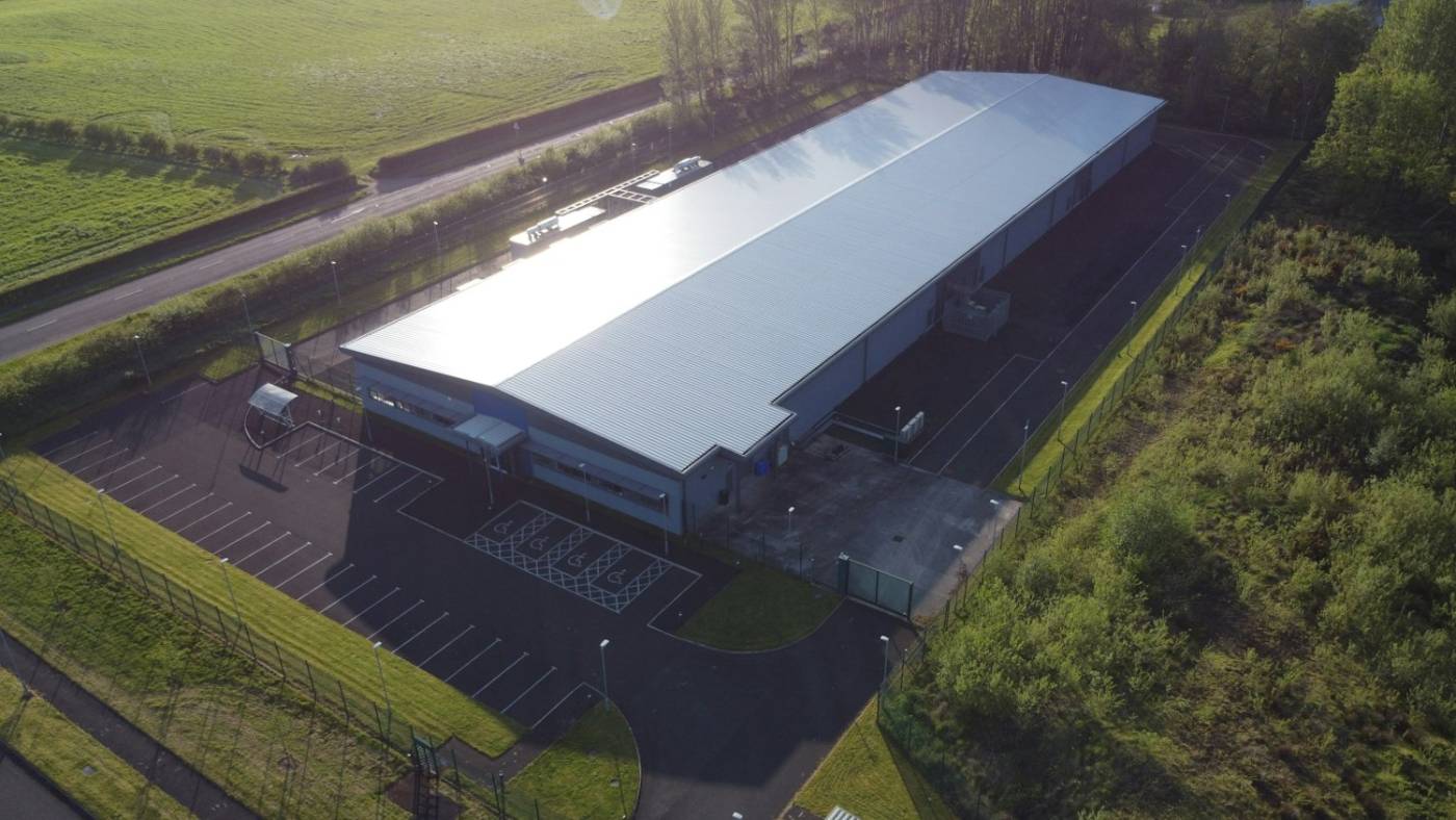 Aerial view of a modern data center building among green fields